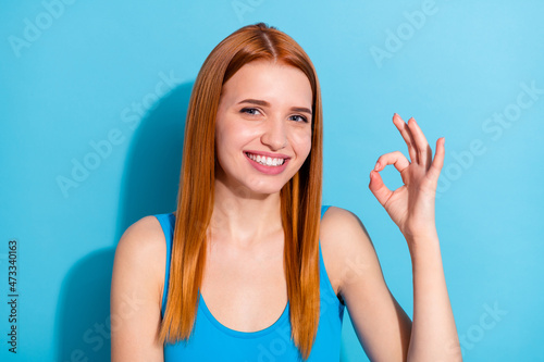 Photo portrait red haired woman wearing pretty singlet showing okay gesture isolated pastel blue color background