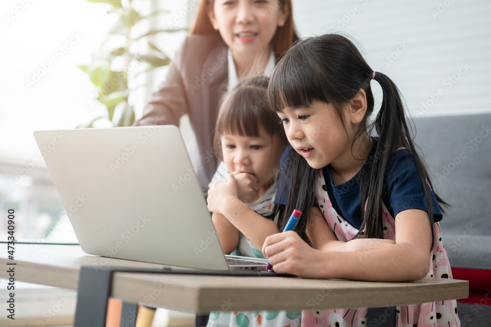 Asian mother with her two grandchildren having fun and playing education games online with a digital computer laptop at home in the living room. Concept of online education and caring from parents. Asian mother with her two grandchildren having fun and playing education games online with a digital computer laptop at home in the living room. Concept of online education and caring from parents.