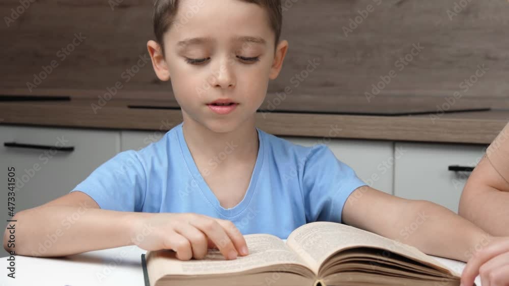 A happy child is reading a book. Mom and son are homeschooled. Distance education. Mom or teacher teaches her son to read. The concept of private education. A happy child is reading a book. Mom and son are homeschooled. Distance education. Mom or teacher teaches her son to read. The concept of private education.