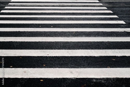 white striped markings of a pedestrian crossing on black asphalt