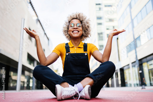 Smiling woman meditating on footpath