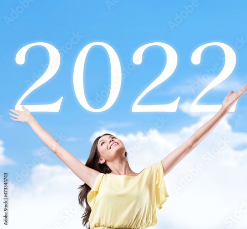 Young woman greets the 2022 against clouds