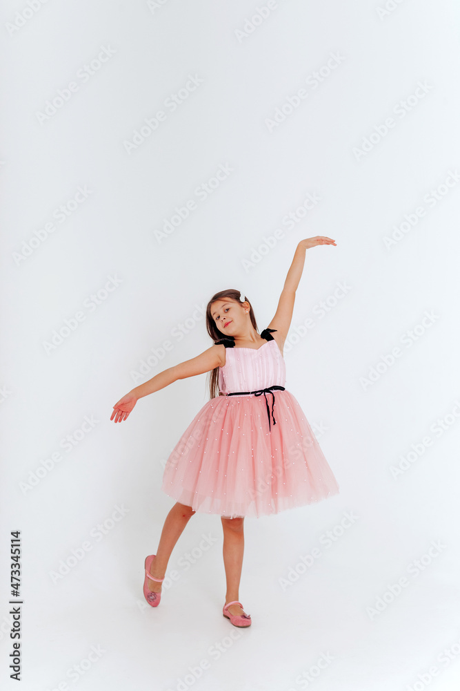 Happy little girl in pink dress dancing on a white background. Space for text. Happy little girl in pink dress dancing on a white background. Space for text.