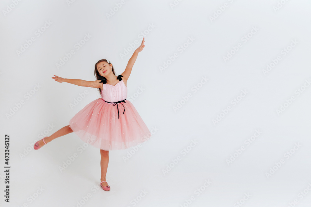 Happy little girl in pink dress dancing on a white background. Space for text. Happy little girl in pink dress dancing on a white background. Space for text.