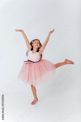 Happy little girl in pink dress jumping on a white background. Space for text. 