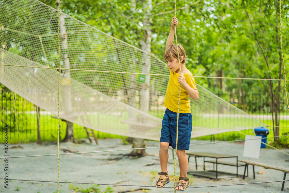 Little boy in a rope park. Active physical recreation of the child in the fresh air in the park. Training for children