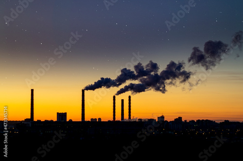 Smoke stack with smoke emission. Plant pipes pollute atmosphere. Industrial factory pollution. Night shooting