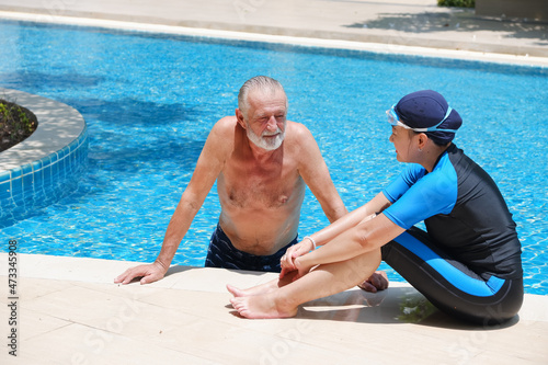 Portrait asia senior woman and caucasian old man resting together in the edge of swimming pool in clubhouse