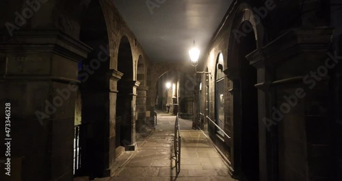 Empty Victoria Street in Edinburgh on a quiet night with traditional shops, the street lights cast gloomy shadows on the buildings lining the dark street. After midnight, the old town becomes empty
