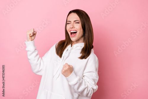 Portrait of attractive cheerful dreamy lucky girl celebrating having fun isolated over pink pastel color background