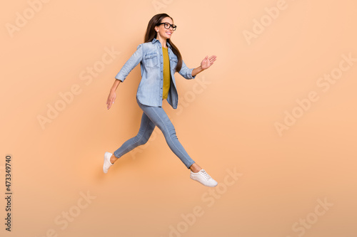 Full size profile side photo of smiling businesswoman running fast hurry work isolated on beige color background