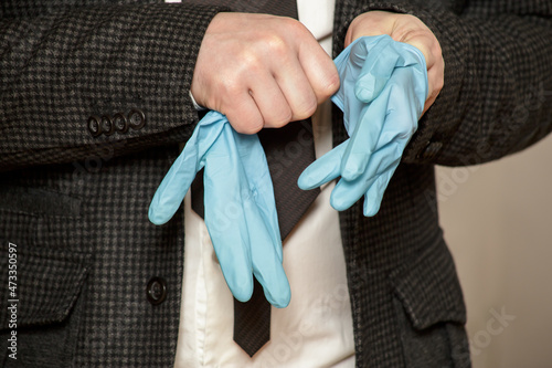 Man puts on protective medical rubber gloves on his hands. Close-up.