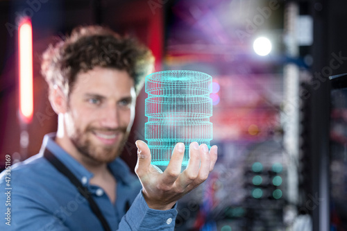 Male IT professional holding hologram of database in server room photo