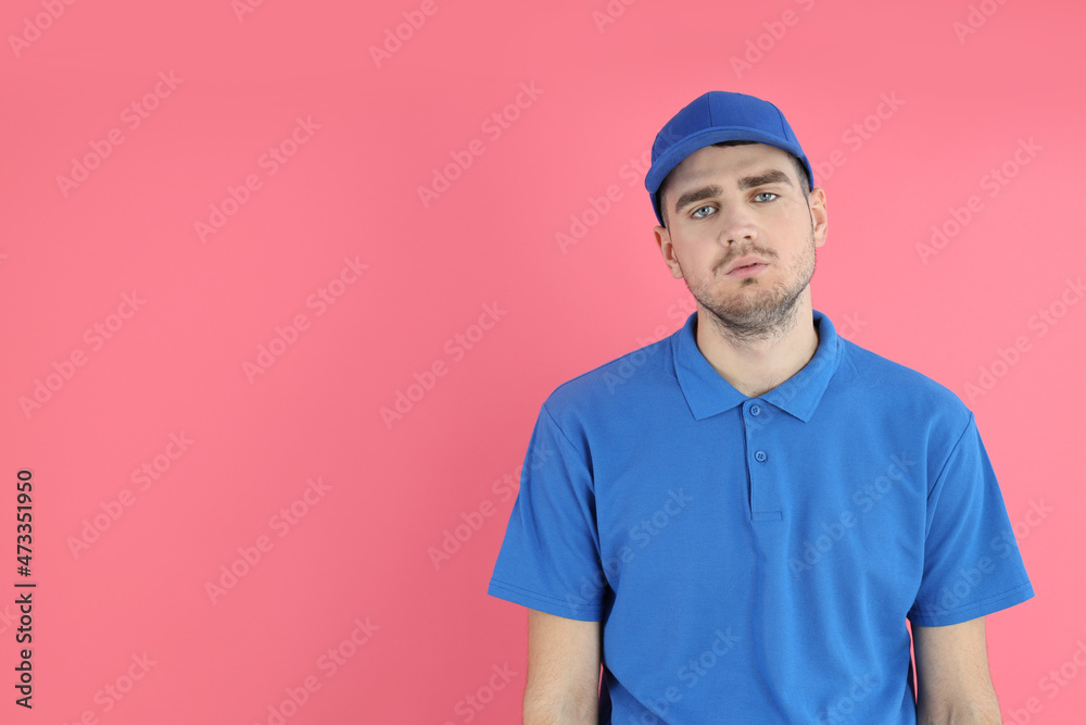 Tired delivery man in cap and t-shirt on pink background Tired delivery man in cap and t-shirt on pink background