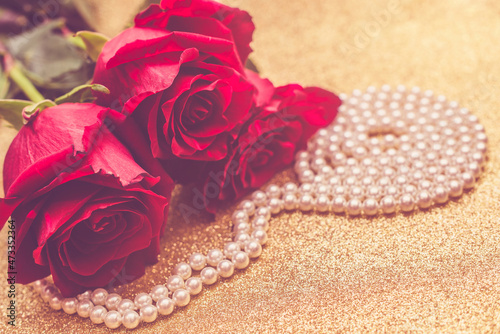 Red rose and pearl necklace on a shiny gold background
 photo