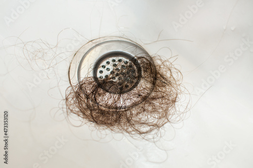 brown hair in the sink drain hole on a metal mesh