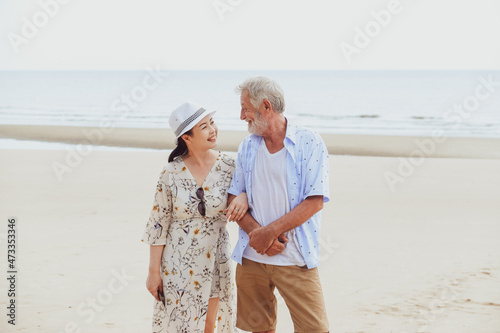 Portrait asia senior woman and caucasian old man relaxing together on the beach