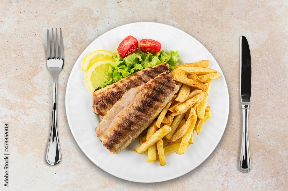 Plate of fried fish fillet with vegetables on the desk Plate of fried fish fillet with vegetables on the desk