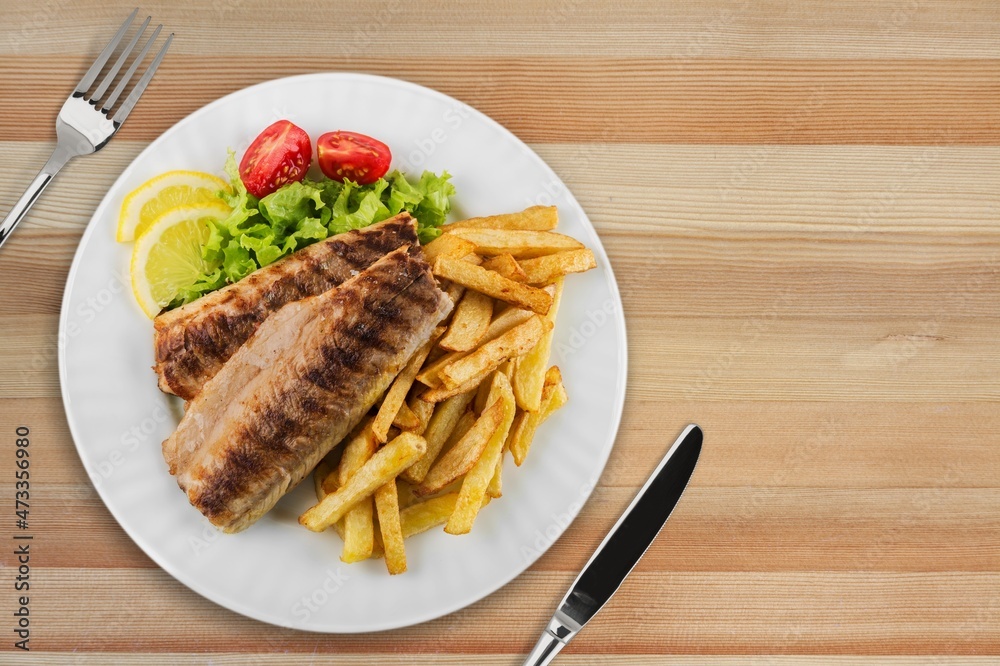 Plate of fried fish fillet with vegetables on the desk Plate of fried fish fillet with vegetables on the desk