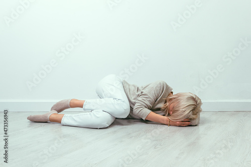 A young girl lies curled up on the floor. Depression concept.