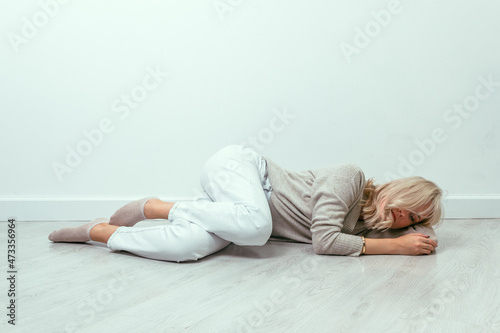 A young girl lies curled up on the floor. Depression concept.