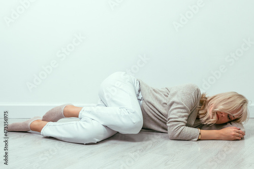 A young girl lies curled up on the floor. Depression concept. © Vladislav Fokin