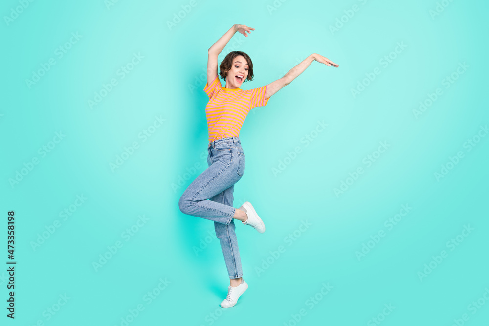 Photo of adorable pretty young lady wear orange t-shirt dancing smiling isolated turquoise color background