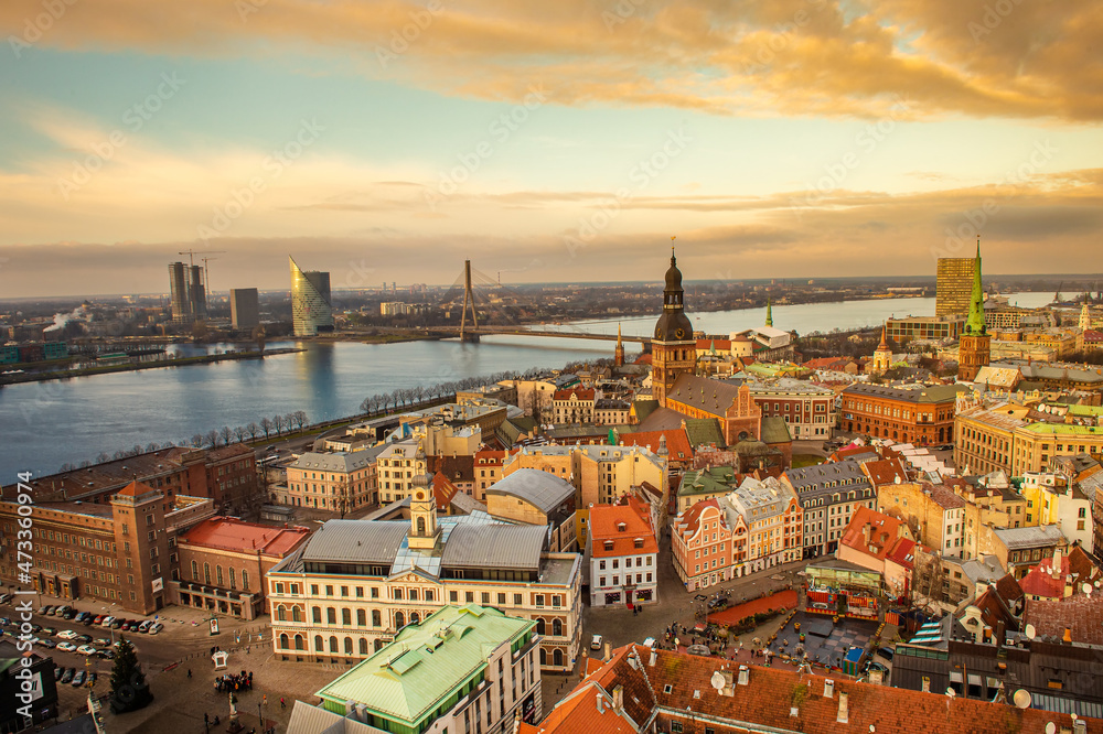 Panorama of the city of Riga on a sunny day, blue sky, morning, sunset, a view of the old town, narrow streets, red brick roofs of houses, cathedrals, a river and bridge.