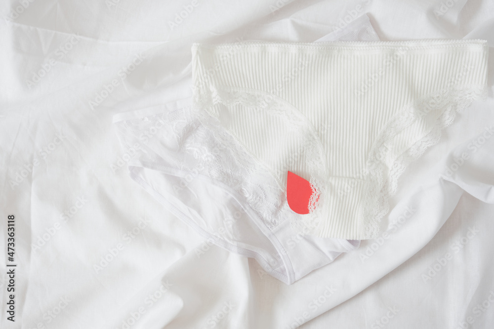 White cotton panties for women with red paper drops like red blood. Concept of menstruation White cotton panties for women with red paper drops like red blood. Concept of menstruation