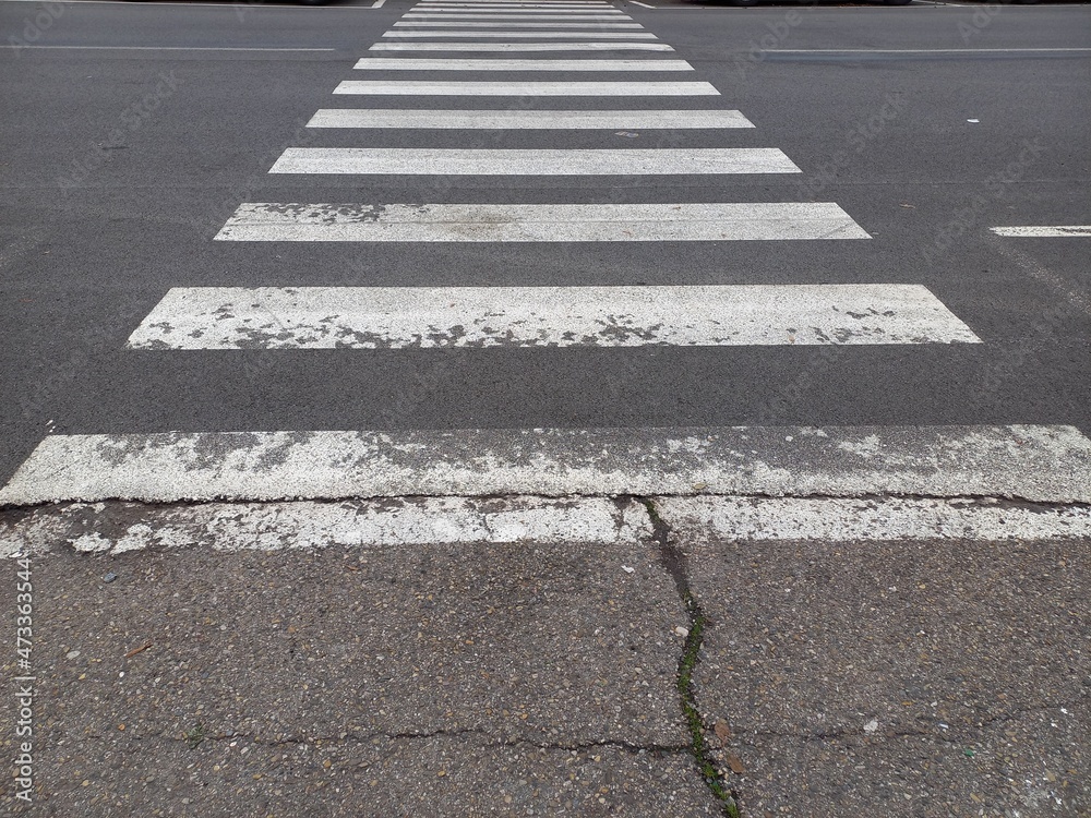 Strisce pedonali sbiadite su asfalto rovinato Strisce pedonali sbiadite su asfalto rovinato