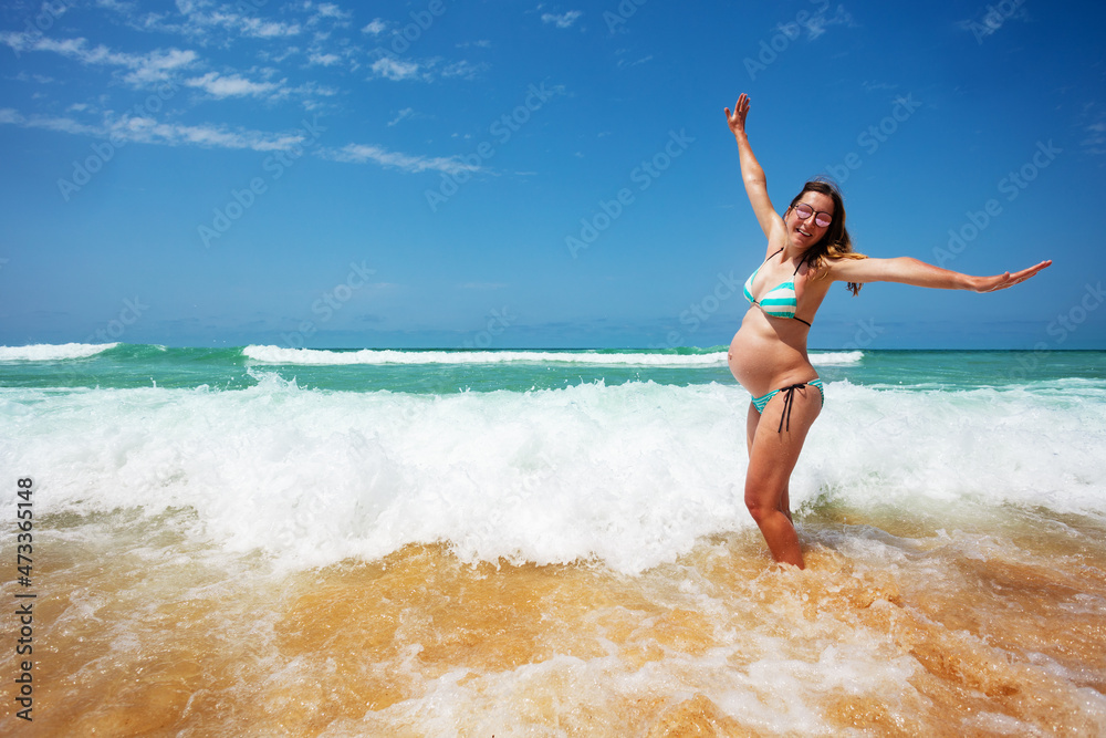 Pregnant woman jump and have fun in the sea waves