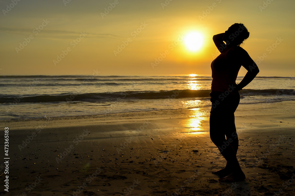 Silhouette of woman posing at sunset on a beach.