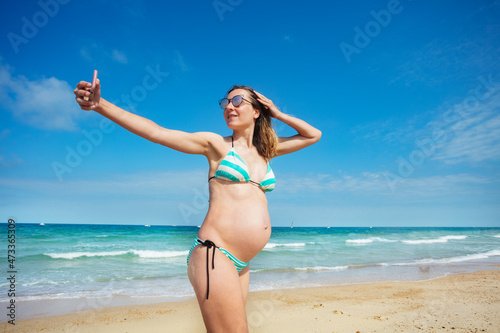 Pregnant woman on sea beach take selfie with phone