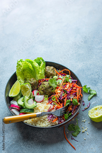 Vegeterian Buddha bowl with lime and peanut slaw, spinach falafels, couscous and salad photo