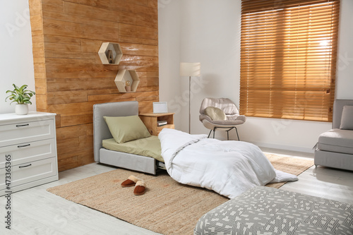Room interior with sleeper sofa near wooden wall. Additional place for guest