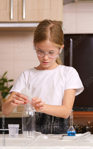 the girl is preparing for a chemical experiment in a home laboratory.