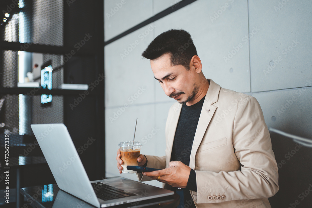Young businessman using phone while working in cafe. Young businessman using phone while working in cafe.