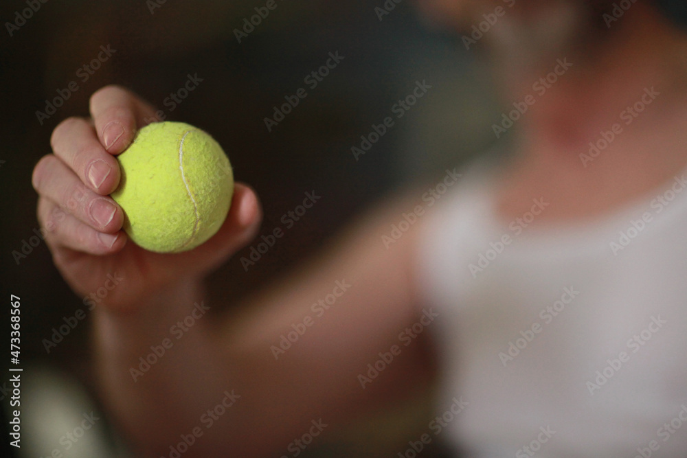 yellow tennis ball in tennis player's hand soft focus