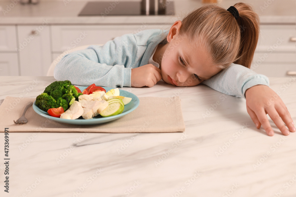 Cute little girl refusing to eat dinner in kitchen Cute little girl refusing to eat dinner in kitchen