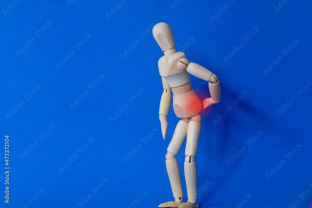 back pain. wooden dummy with hand on back in pain. need for physical therapy