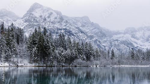 snow covered mountains in winter next to lake