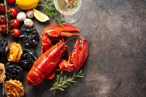 Food dark background with pasta, cooked lobster and white wine. Top view