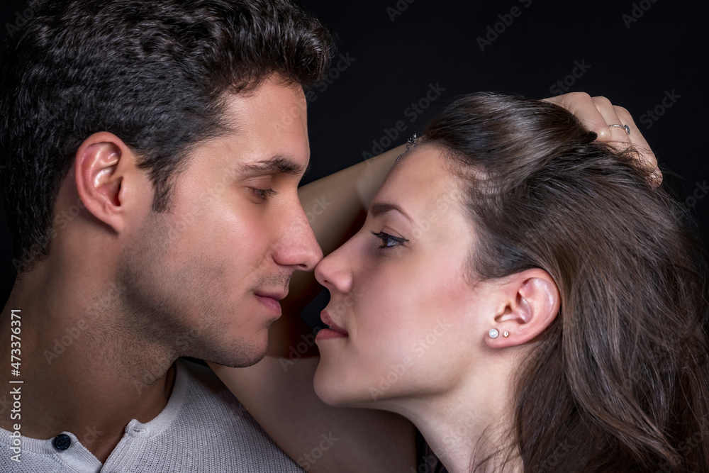 Portrait of a young loving couple. Young engaged couple look into each other's eyes face to face. Portrait on dark background. Portrait of a young loving couple. Young engaged couple look into each other's eyes face to face. Portrait on dark background.