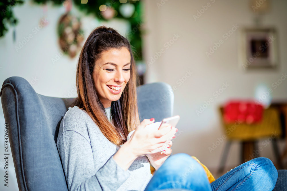 Happy woman using her mobile phone and text messaging while relaxing at home Happy woman using her mobile phone and text messaging while relaxing at home