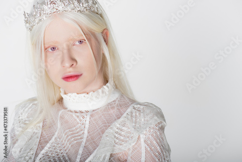 Portrait of young albino woman in crown and blouse looking at camera isolated on white.