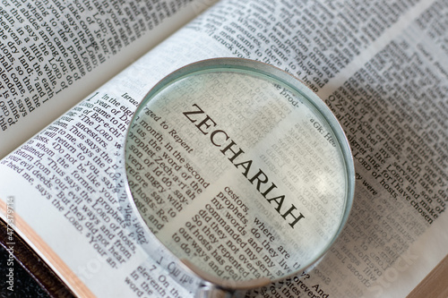 Open Holy Bible Book Zechariah prophet Old Testament Scriptures with a magnifying glass. The Christian biblical concept of studying the Word of God Jesus Christ. A close-up.