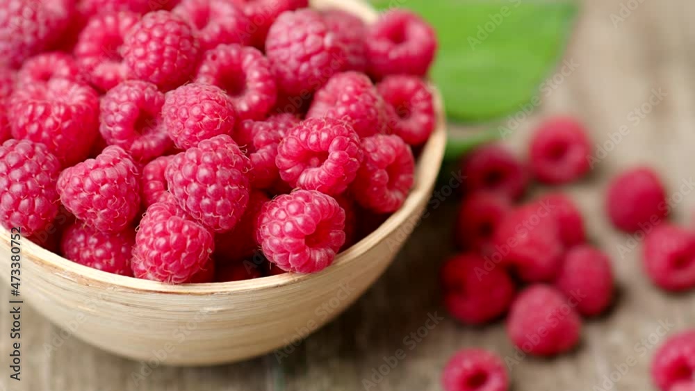 Fresh ripe red raspberries with leaves in a bowl on rustic old wooden table in 4K VIDEO. Organic farming, healthy food, BIO viands, back to nature concept. Fresh ripe red raspberries with leaves in a bowl on rustic old wooden table in 4K VIDEO. Organic farming, healthy food, BIO viands, back to nature concept.