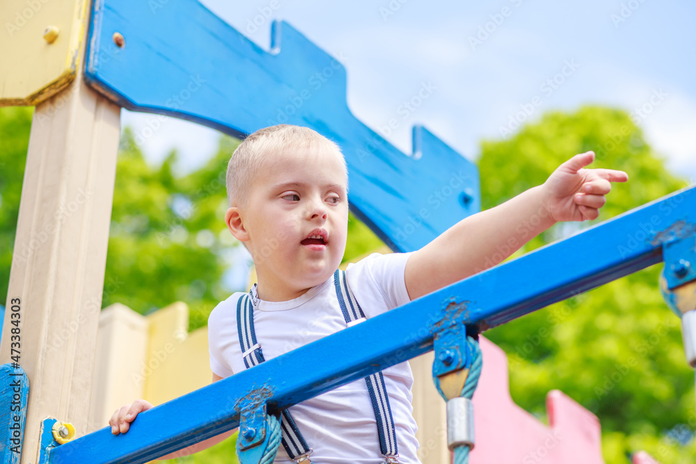 A boy with Down syndrome is playing on the playground, the child has a developmental delay.
A boy with Down syndrome is playing on the playground, the child has a developmental delay.