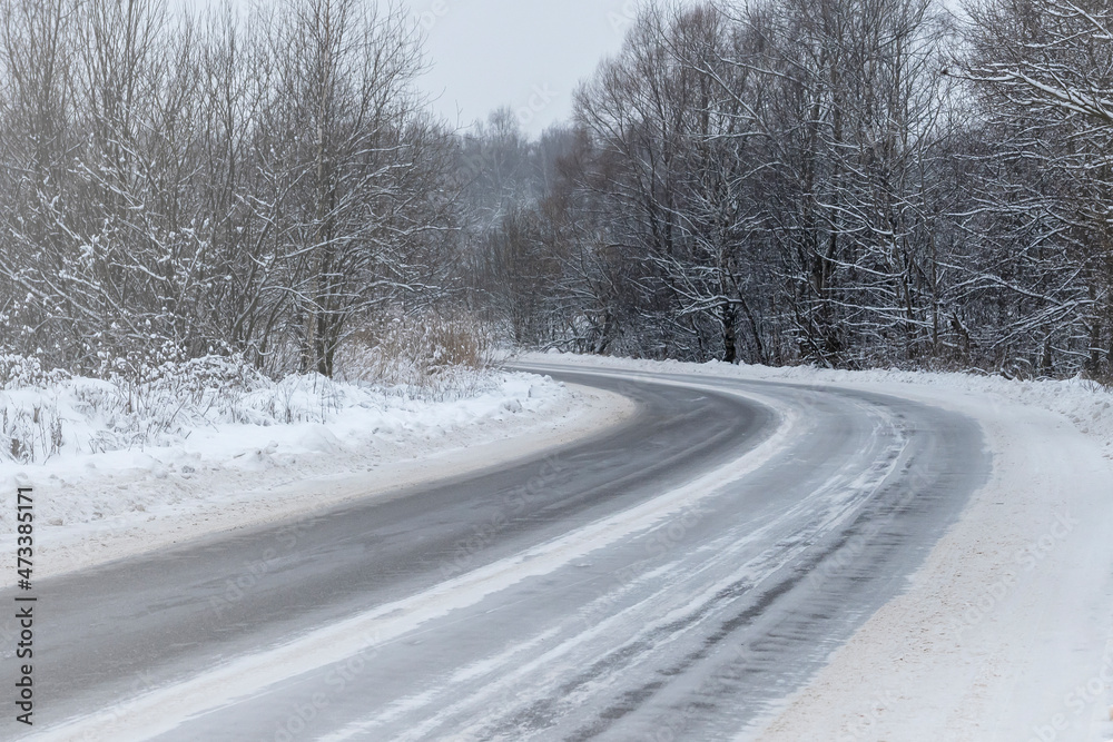 An icy winter road. A bend in the road in the forest.