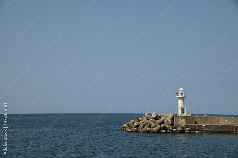 灯台のある穏やかな漁港からの水平線の眺め